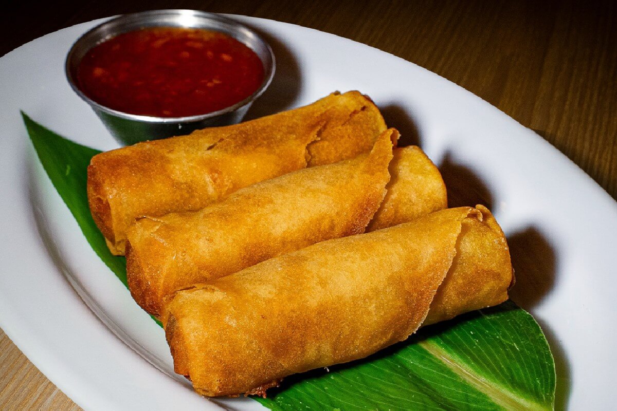 Close-up of authentic handmade and fried vegetable spring rolls on a plate revealing a fresh vegetable filling.
